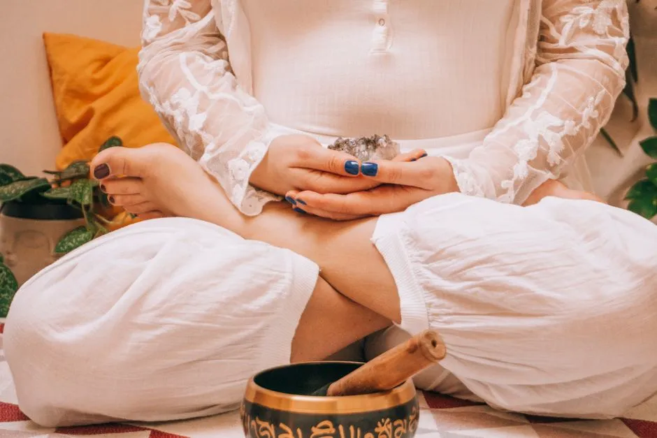 Woman seated in lotus position holding a crystal near a singing bowl