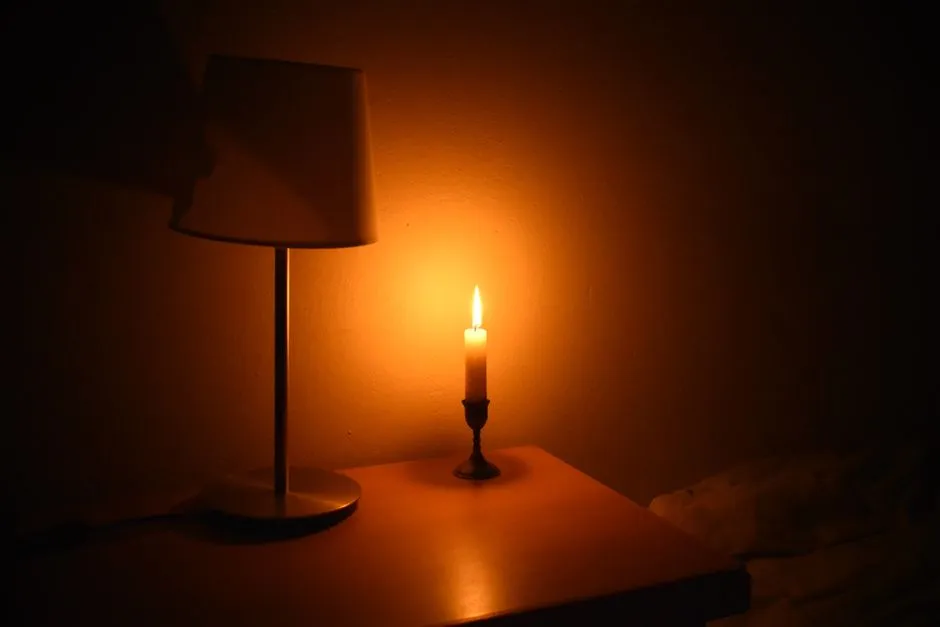 Lit candle on a bedside table in a dim, restful bedroom
